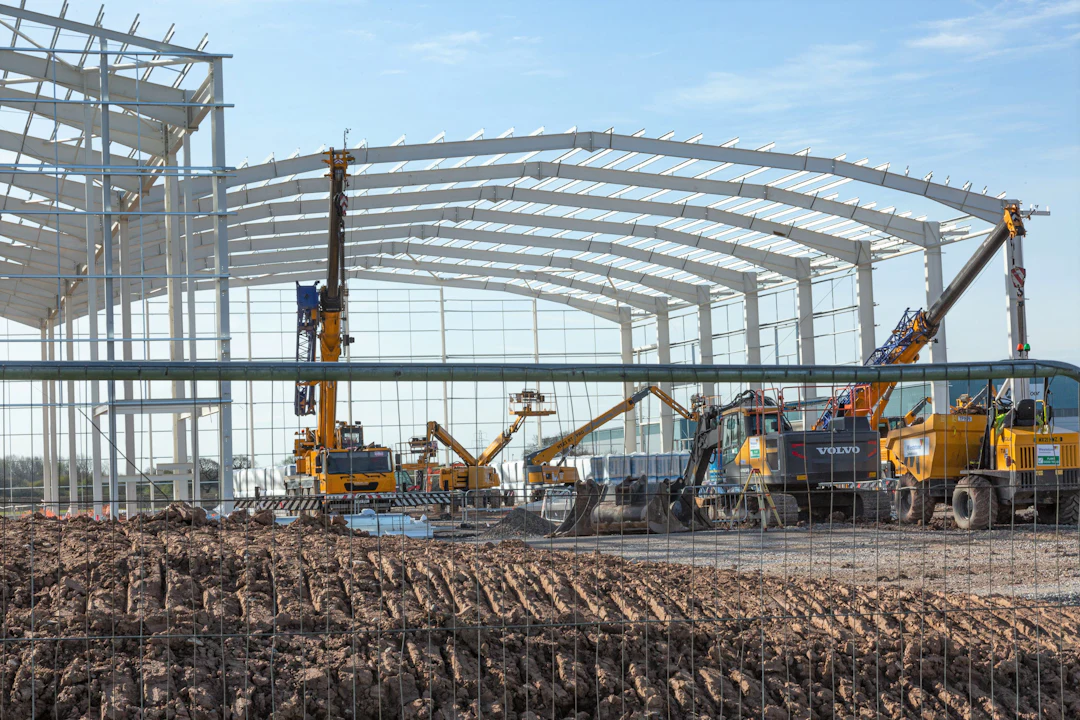 Structural steel frame of a large industrial building being erected with cranes and lifts