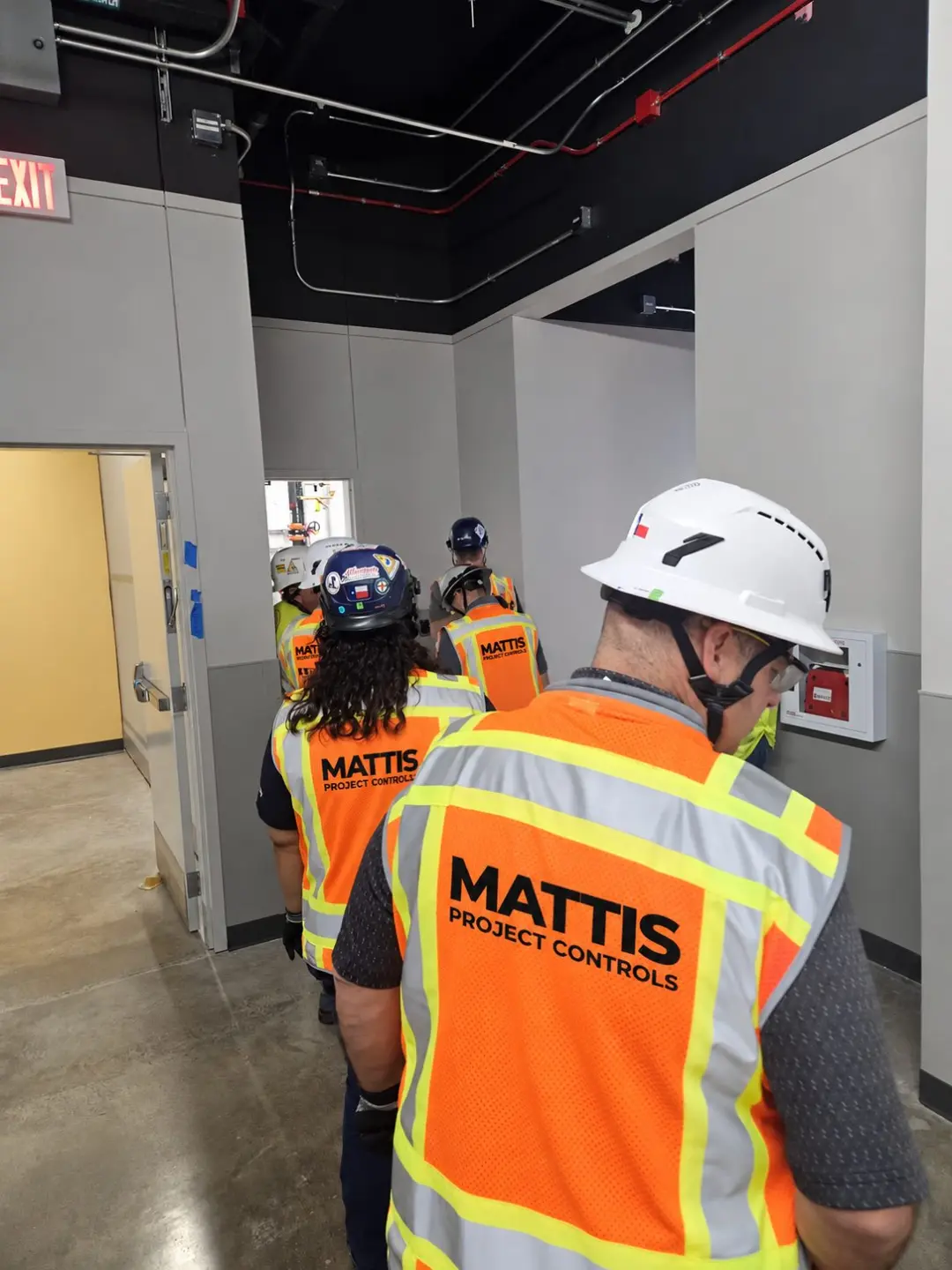 Mattis Project Controls team in branded safety vests and hard hats walking a data center corridor